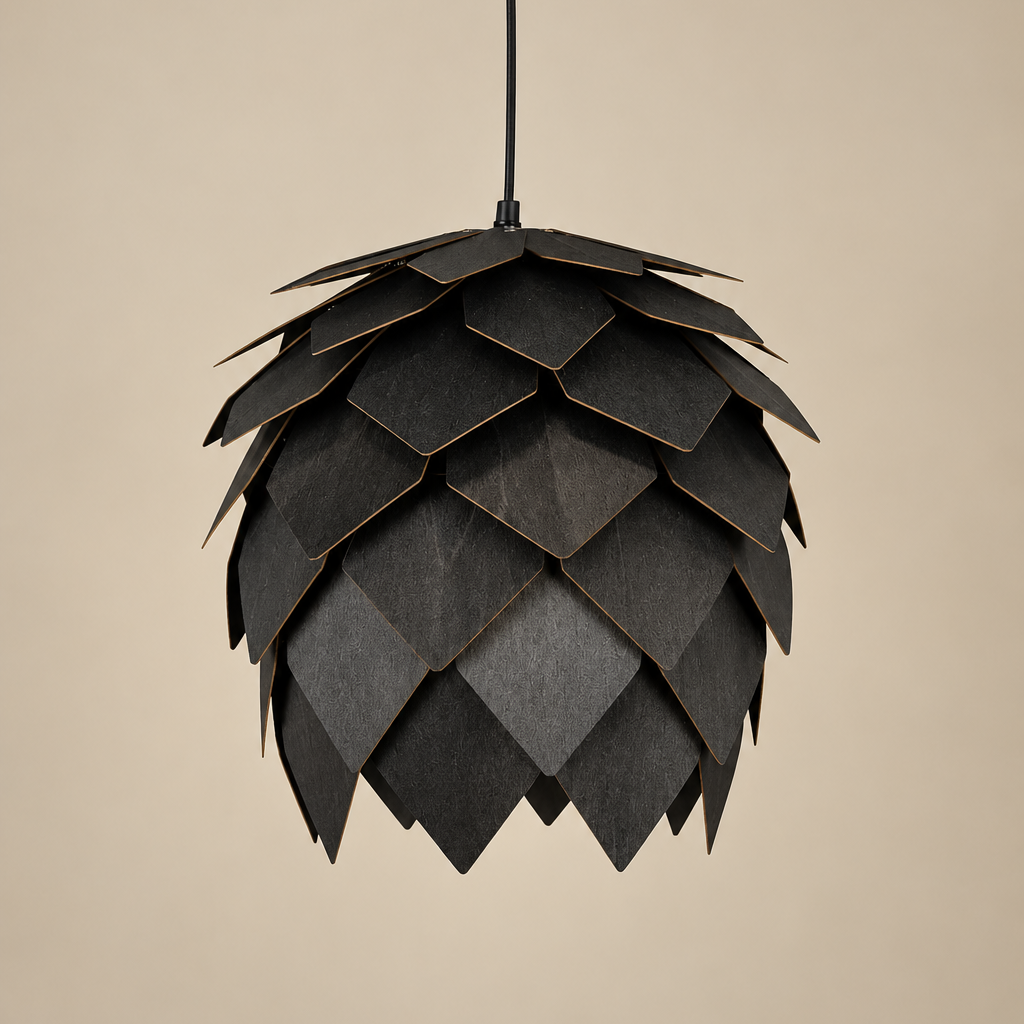 Black sculptural pendant light inspired by the shape of an artichoke, featuring overlapping textured panels, a rounded silhouette and black suspension cord against a warm beige background.