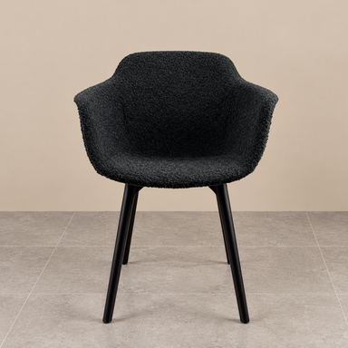 Discover our Black Bouclé Sculptural Dining Chair. Featuring luxurious textured upholstery, curved armrests and sleek black legs for a contemporary look.