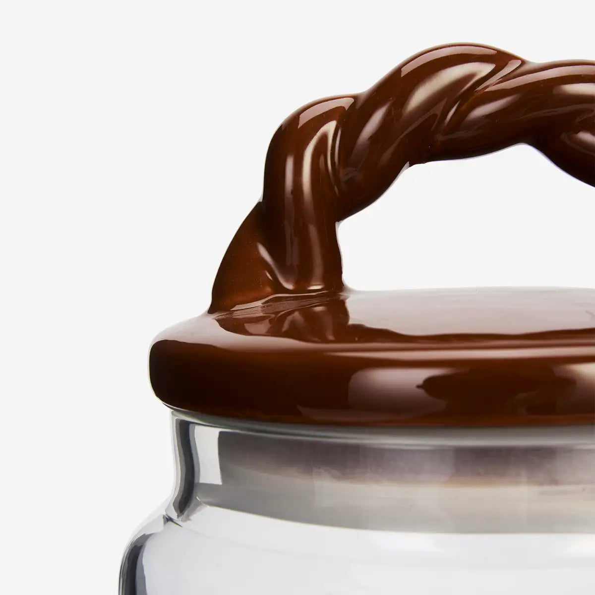 Glass jar filled with roasted coffee beans and topped with a glossy brown braided-handle ceramic lid.