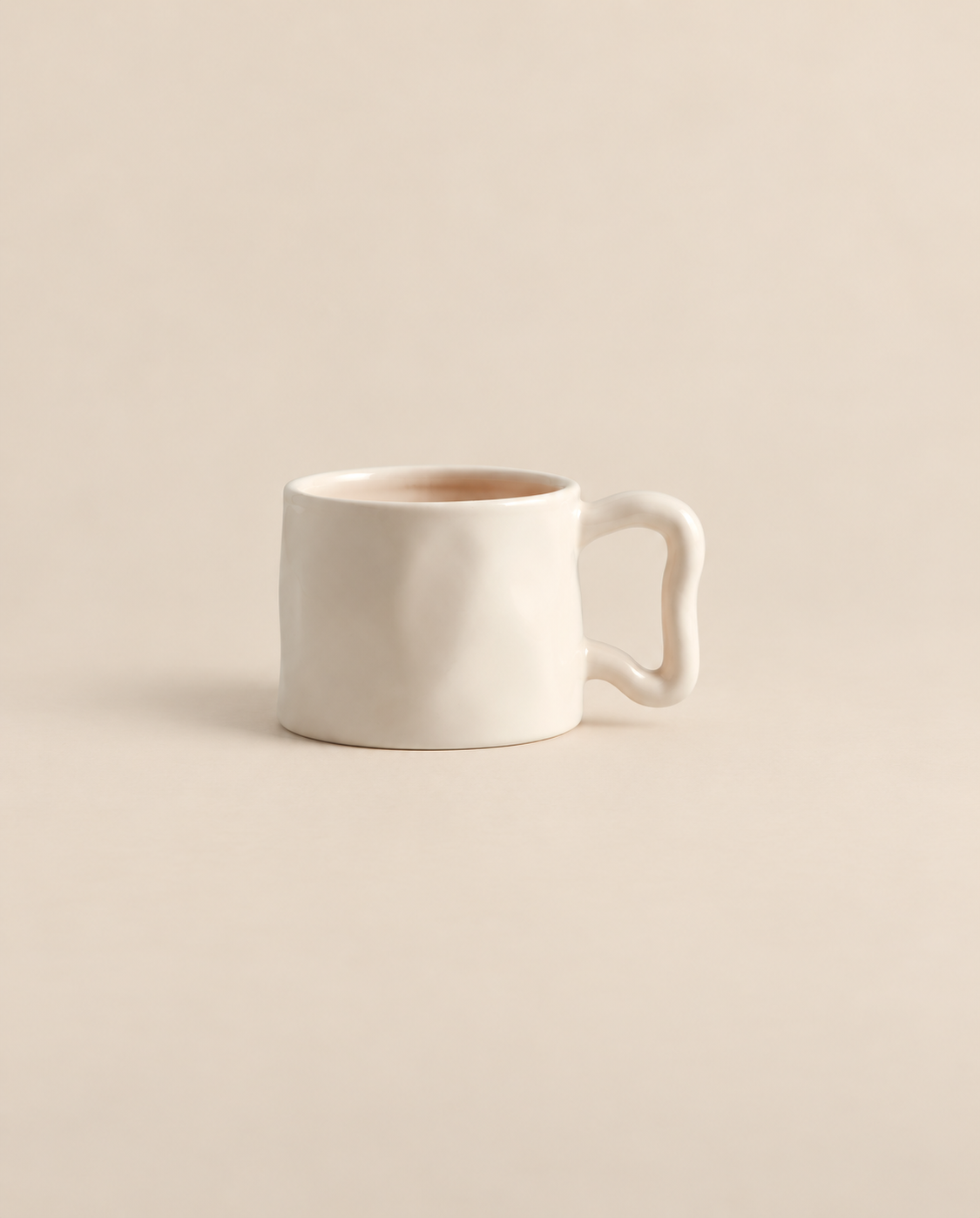 Ivory ceramic mug with a curved sculptural handle on a light beige background.