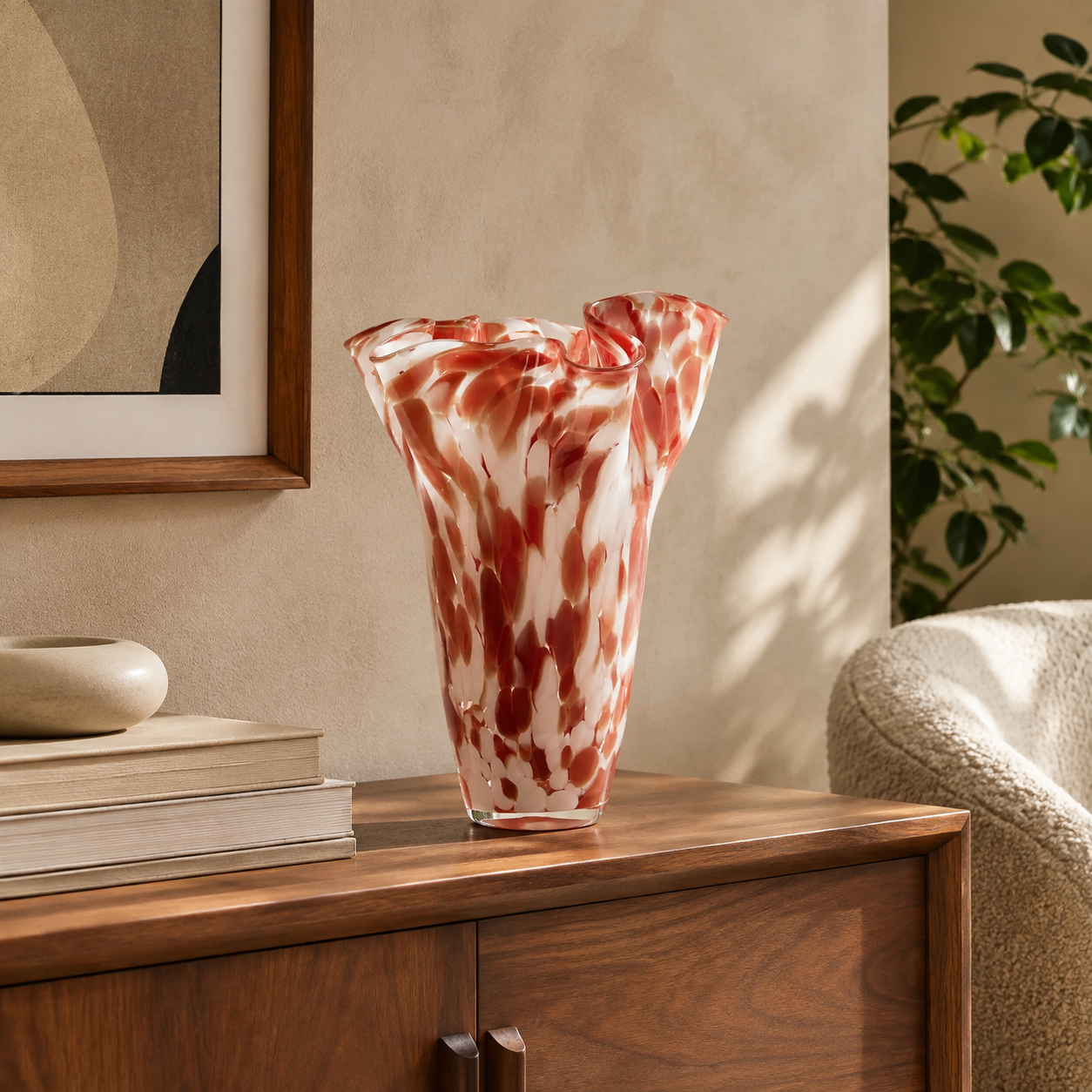 Pink and red sculptural wavy glass vase displayed on a walnut sideboard in a mid-century modern living room.