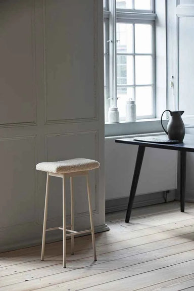 beige metal bar stool with teddy upholstery styled in a scandinavian home interior.