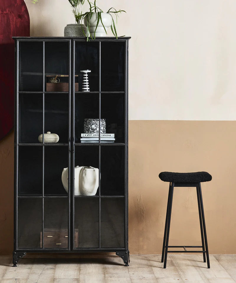 Black metal bar stool with teddy upholstery styled in a modern home interior.