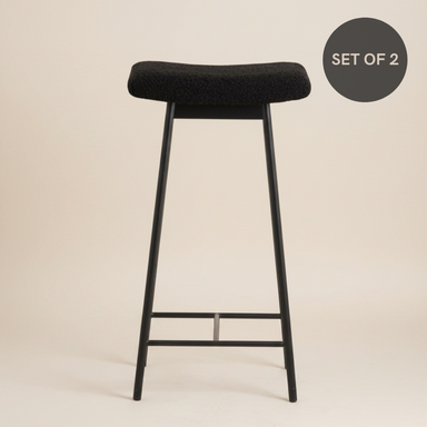 Black metal bar stool with soft teddy upholstery, a padded seat and a contemporary design.