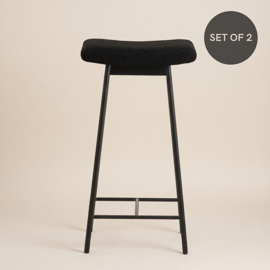 Black metal bar stool with soft teddy upholstery, a padded seat and a contemporary design.