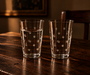 Vintage-inspired clear drinking glasses featuring delicate white polka dots, styled on a dark walnut table.