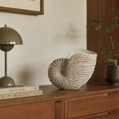 Handcrafted sculptural shell vase styled on a console table in a contemporary home interior.