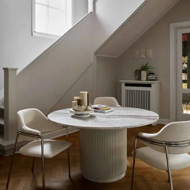 Natural beige round marble dining table styled in a contemporary dining room with modern décor.