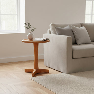 Round mid-century side table styled beside a sofa in a contemporary living room.