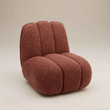 Sculptural red boucle sofa chair with soft textured upholstery, curved lines and a contemporary design.