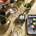 Set of 2 green Art Deco glasses styled on a contemporary dining table.