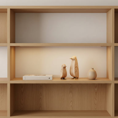 Set of 2 plywood penguin ornaments styled on a shelf in a contemporary home.