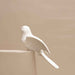 White ceramic dove hanging decoration styled on a decorative branch in a contemporary home.